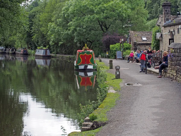 People outside the stubbings wharf pub on the rochdale canal in hebden bridge with barges and houseboats moored along the bank — Stok fotoğraf