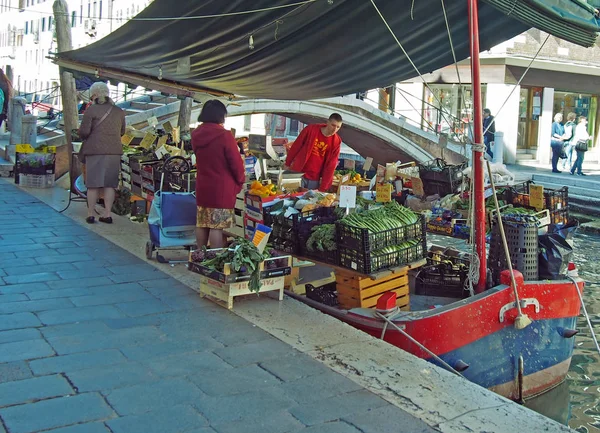 Люди делают покупки на овощной ларьке на лодке в канале на историческом рынке в районе Rialto Venice — стоковое фото