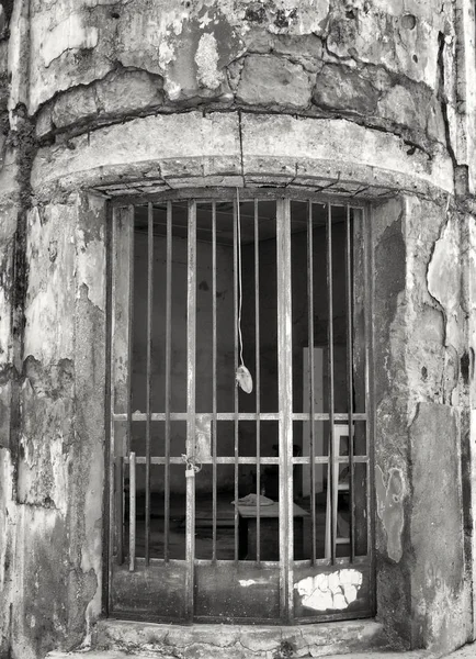 Monochromatický obraz rezavých kovových mříží na dveřích staré opuštěné opuštěné budovy s popraskanými stěnami — Stock fotografie