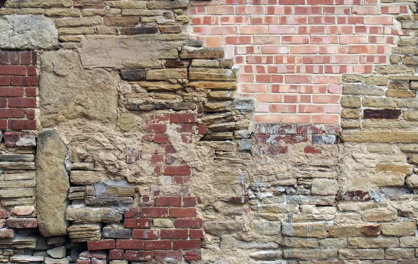 Grande parede velha feita de tijolos mistos e pedra com muitos remendados confusos e reparos irregulares — Fotografia de Stock
