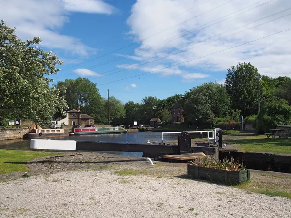 Blick auf die Schleusentore am Brighouse-Becken auf dem ruhigeren und steilen Schifffahrtskanal mit Kähnen und von Bäumen umgebenen Gebäuden am Kanal — Stockfoto