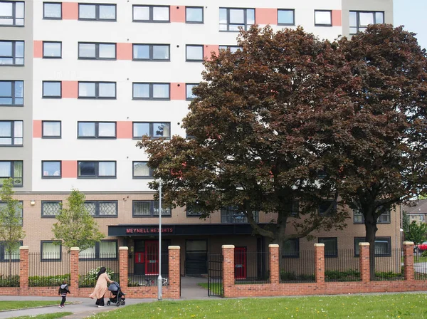 Una mujer con un niño empuja un cochecito más allá de la un edificio de apartamentos de vivienda del consejo en Holbeck páramo en Leeds West Yorkshire —  Fotos de Stock