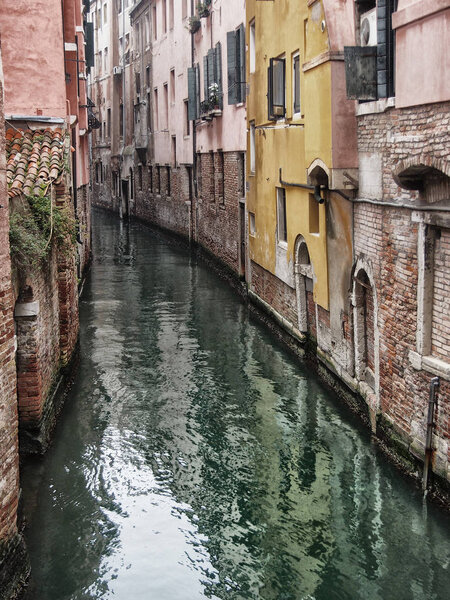 small canal in venice with elegent old buildings reflected in gr