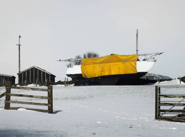 Un barco grande en un campo cubierto de nieve en una granja cubierta por un grito —  Fotos de Stock