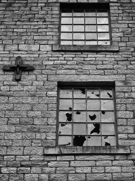 Ventanas rotas en un vacío abandonado vandalizado viejo edificio de piedra —  Fotos de Stock