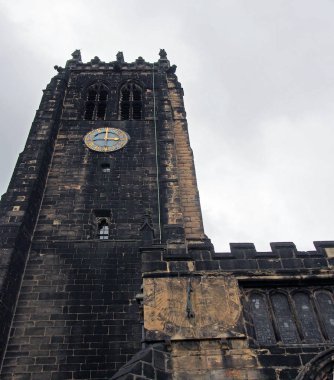 Ortaçağ kilise kulesi ve saatinde karanlık taş işçiliğiyle Batı Yorkshire 'daki halifax Minster manzarası.