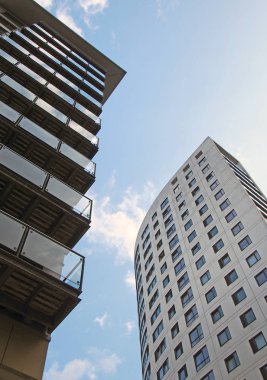 Clarence Evi 218 feet uzunluğunda modern bir daire ve perakende satış binası ve Leeds rıhtımındaki bitişik daireler mavi bulutlu bir gökyüzüne karşı.