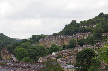 a view of the streets and houses of hebden bridge between trees and calder valley landscape in west yorkshire clipart