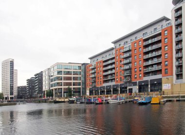 Batı Yorkshire 'daki Leeds rıhtımındaki modern apartmanların yanında demirlemiş eski yüzen evler.