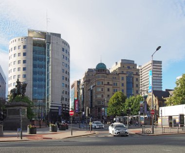 Şehir meydanındaki taksiler, Leeds West Yorkshire 'da şehir binalarının ve anıtların önünden geçen parlak yaz güneşiyle birlikte.