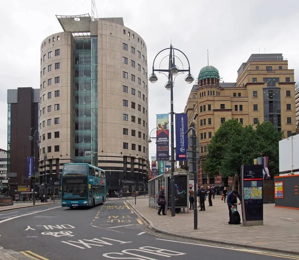 Autobuses y peatones carretera en leeds plaza de la ciudad con altos edificios de oficinas de fila del parque — Foto de Stock