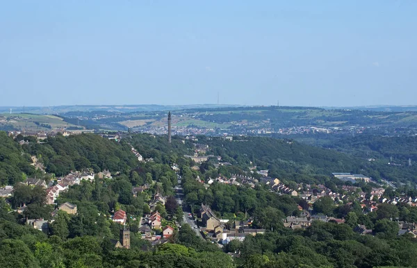 Uma vista panorâmica da cidade de yorkshire ocidental de cima com ruas e casas cercadas por árvores e campos e a torre wainhouse histórica em uma encosta — Fotografia de Stock