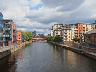 Nehir kıyısı manzaralı, deniz kenarındaki apartman daireleri ve uzak köşeli köprülü binalar.