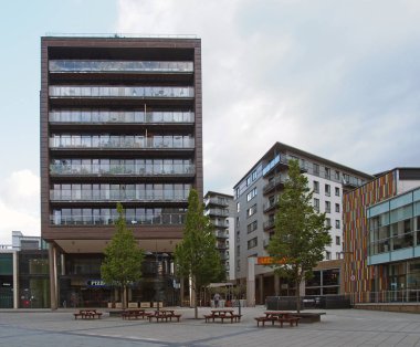 Meydanı çevreleyen, ağaçlı ve banklı Leeds rıhtımındaki bar restoranları ve modern apartmanlar.
