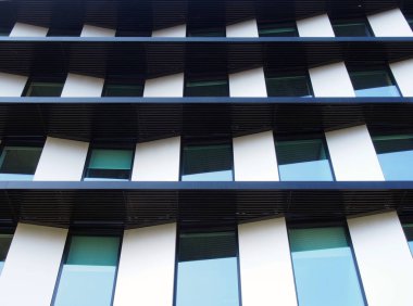Açılı geometrik panelleri ve yansıyan pencerelerden oluşan fütürist modern bir binanın cephesi
