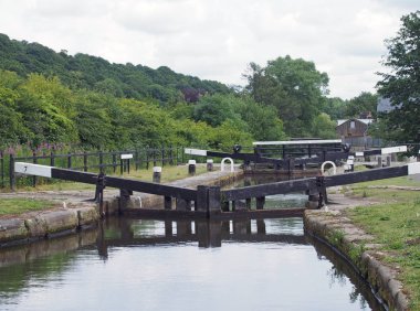 broadbottom lock on the rochdale canal on the outskirts of mytholmroyd west yorkshire with summer trees lining the valley and buildings of the town in the distance clipart