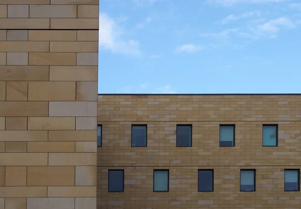 작은 창문 과푸른 하늘 이 기하학적으로 반복되는 형태를 갖춘 현대식 석조 건물의 전면 — 스톡 사진