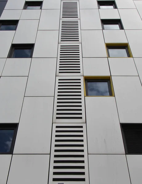 Закрытие металлических облицовочных панелей серебряного цвета на современном здании с повторяющимися окнами и геометрическим дизайном сетки — стоковое фото