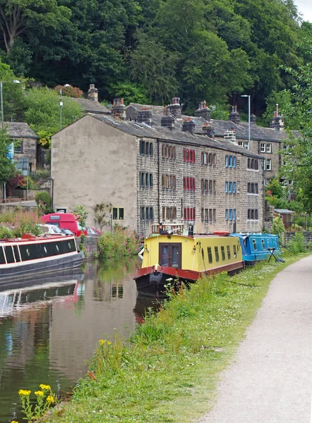 Le canal rochdale traversant le pont hebden avec des bateaux amarrés reflétés dans l'eau et des bâtiments en pierre entourés d'arbres ; — Photo