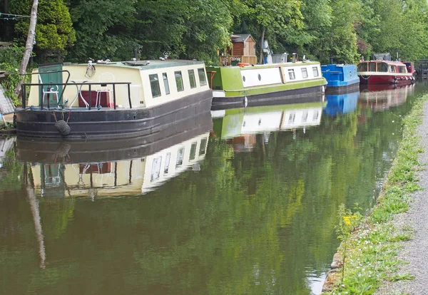 Úzké čluny a čluny kotvíné na kanálu Rochdalu v Hebden Bridge obklopené zelenými letní stromy — Stock fotografie