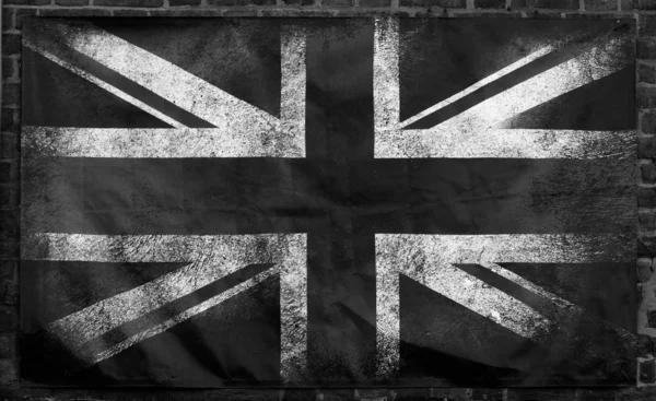 검게 구겨진 가장자리가 벽돌 벽 배경 위에 있는 낡고 더러워진 유니언 잭 영국 국기의 모노크롬 이미지 — 스톡 사진