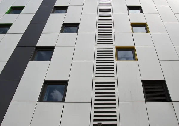 Close-up de painéis de revestimento de metal de cor prata em um edifício moderno com janelas repetidas e design de grade geométrica — Fotografia de Stock