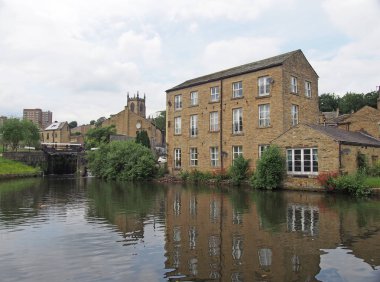 a scenic view of the town of sowerby bridge in west yorkshire with buildings reflected in the canal basin and buildings behingd the lock gates