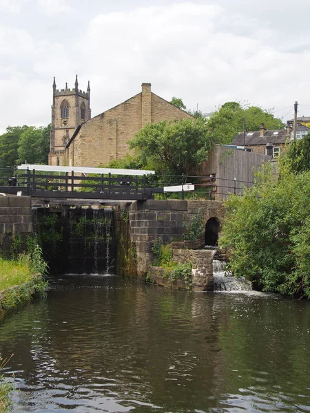 Batı Yorkshire 'daki Sowerby Köprüsü' ndeki kanalın kapılarını kilitle. Etrafı ağaçlarla çevrili tarihi Hristiyan kilisesi binasıyla. — Stok fotoğraf