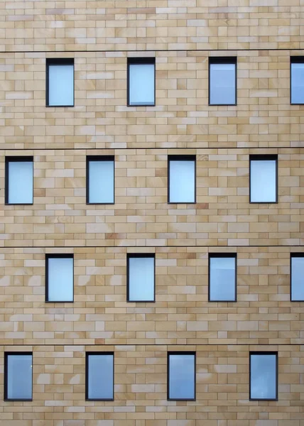 작은 창문들 이 기하학적으로 반복되는 무늬가 있는 현대식 석조 건물의 전면 — 스톡 사진
