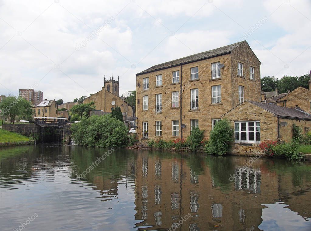 a scenic view of the town of sowerby bridge in west yorkshire with buildings reflected in the canal basin and buildings behingd the lock gates