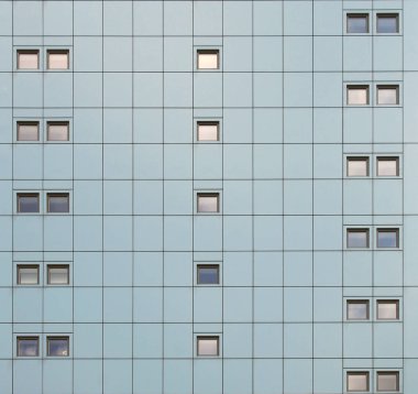 geometrik metalik kaplama ve tekrarlayan desen pencereleri olan modern bir binanın tam çerçeve cephesi