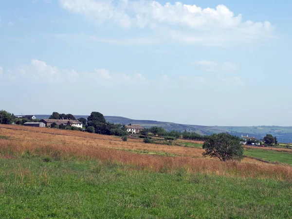 Uma vista panorâmica fazendas entre campos cobertos de grama perto blackshaw cabeça no oeste de yorkshire com distantes colinas pennine contra um céu azul de verão — Fotografia de Stock