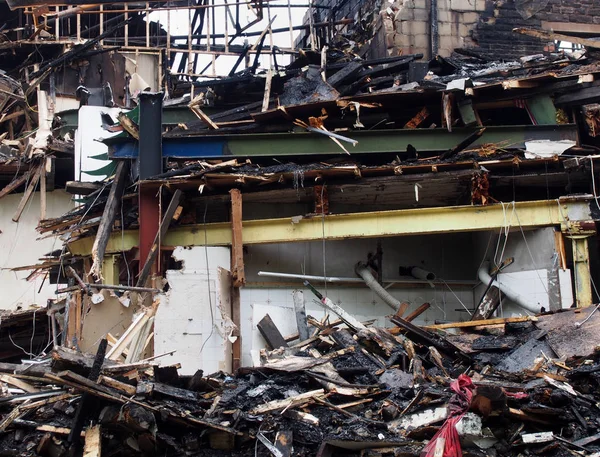 Zwart verbrand puin en hout en stalen balken in een ingestort gebouw verwoest door brand — Stockfoto