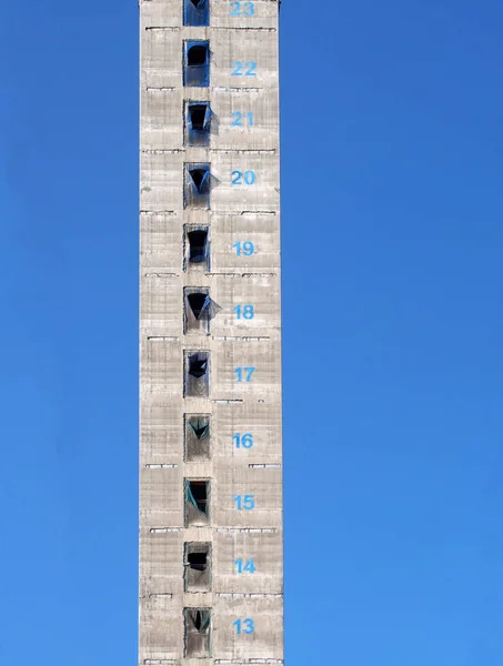 Eine hohe Betonkonstruktion und der Dienstleistungskern eines im Bau befindlichen Wolkenkratzer-Neubaus mit farbig markierten Stockwerken vor blauem Himmel — Stockfoto