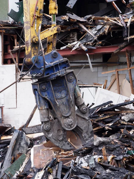 A demolition claw removing debris and rubble from a wrecked building damaged by fire — Stock Photo, Image