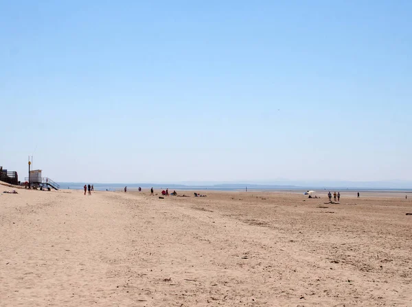 People walking and relaxing on formby beach on the sefton coast in merseyside with blue summer sea and sky — Stock Photo, Image