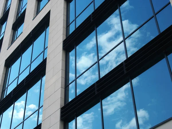 거대 한 거울 이 있는 현대식 상업 건물의 어렴풋이 보이는 파란 하늘 과흰 구름을 반사하는 창문 — 스톡 사진