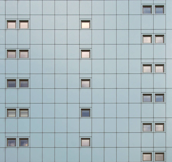 Full frame facade of a modern building with geometric metallic cladding and repeating pattern windows