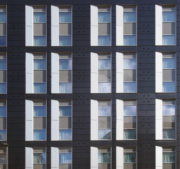 Facade of a large black and white modern commercial building with repeating windows and geometric panels — Stock Photo, Image