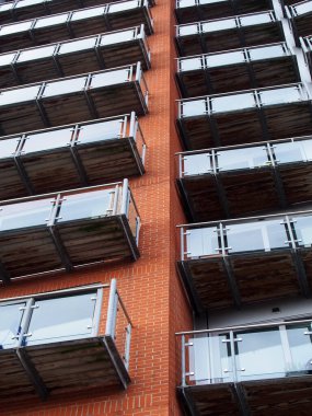 Tuğla duvarlı ve cam balkonlu modern apartman manzaralı.
