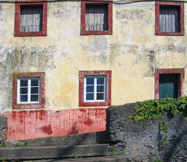 Tipik bir İspanyol evinin ön cephesi soluk sarı ve kırmızı renklerle boyanmış Funchal, Tenerife 'de bitkilerle çevrili gri bir duvarla çevrili.