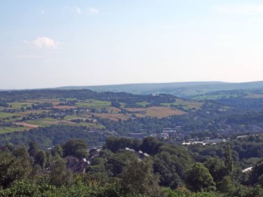 Batı Yorkshire kırsalının panoramik manzarası. Warley köyü çevresi ağaçlık arazi ve uzak Pennine tepeleriyle çevrili.
