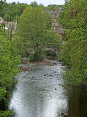 Yaz ağaçlarıyla çevrili nehir ve köprüyle Hebden Köprüsü manzarası