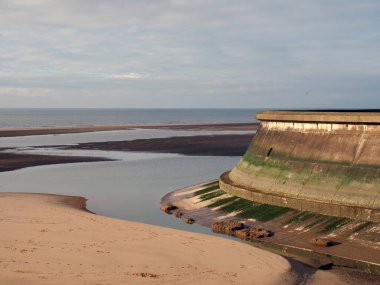 Blackpool Lancashire 'daki eski kayık havuzunun beton kıyısı. Etrafı sularla çevrili. Mavi deniz ve bulutlarla çevrili.