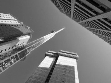 Tek renkli, dikey bir vinç, yüksek apartmanlı bir inşaat alanında çalışıyor.