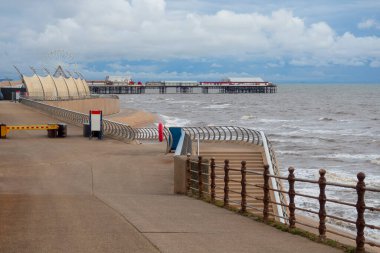 traffic barrier pedestrian promenade on Blackpool seafront with steps down to the sea and central pier in the distance