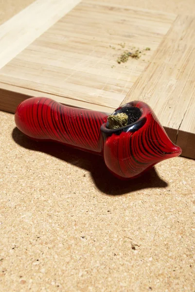 木製テーブル上のマリファナと赤い喫煙パイプ — ストック写真