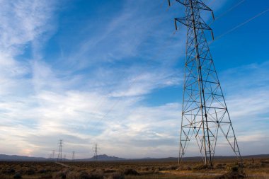Mavi gökyüzü ve bulutlar ile çöl elektrik kuleleri 