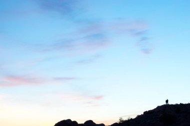 Gün batımında dağın zirvesinde duran insanların silueti
