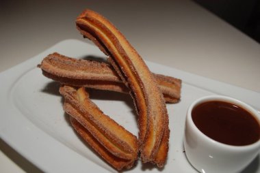 Churros, fincan sıcak çikolata ile tabakta kızarmış hamur pasta